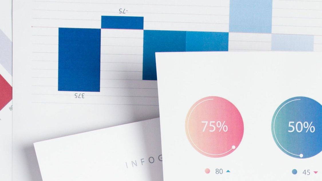 Hands holding a printed financial report with pink and blue charts